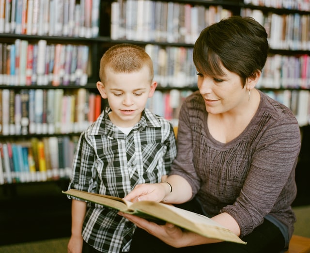 woman helping young boy learn to read - SPD tuition and coaching england uk