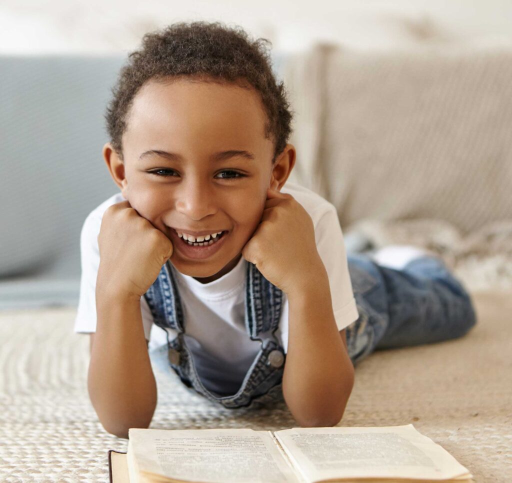 portrait-schoolboy-lying-floor-reading-book-library-school